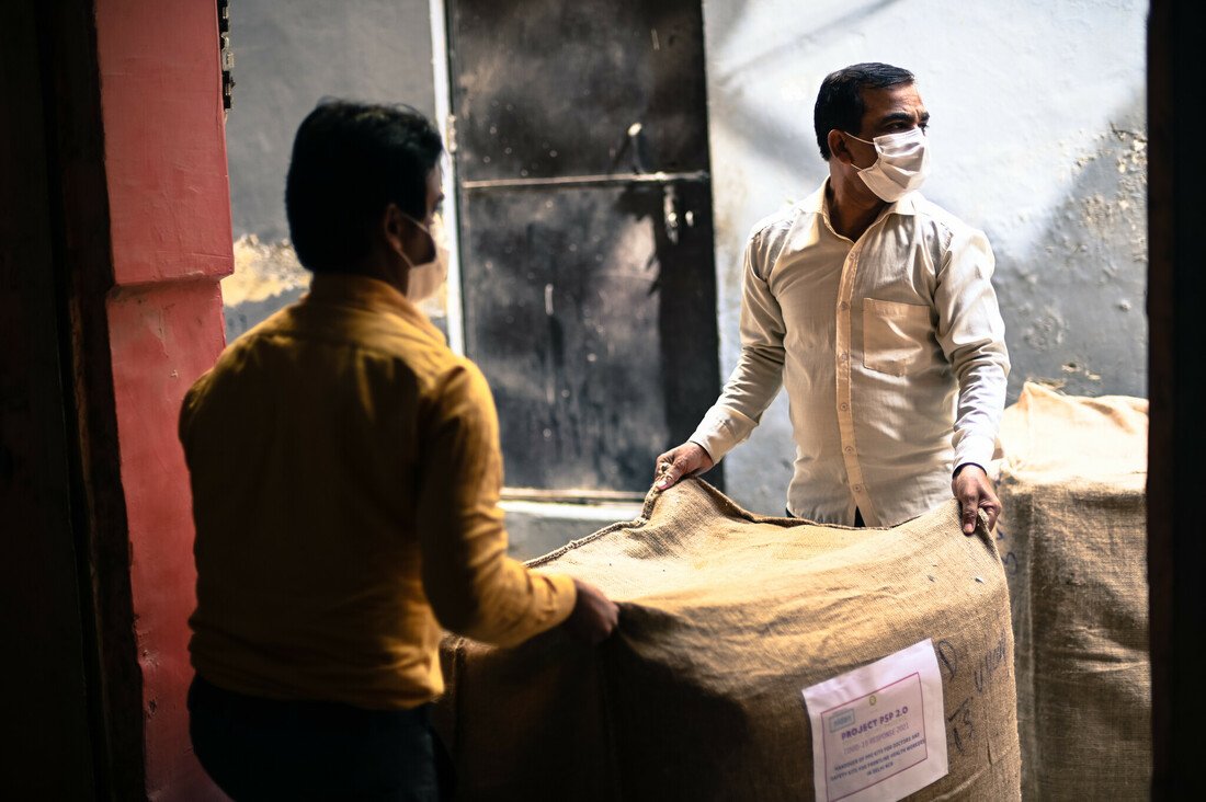 Workers take bags of PPE kits to be transported to hospitals out of a storage facility in East Delhi.